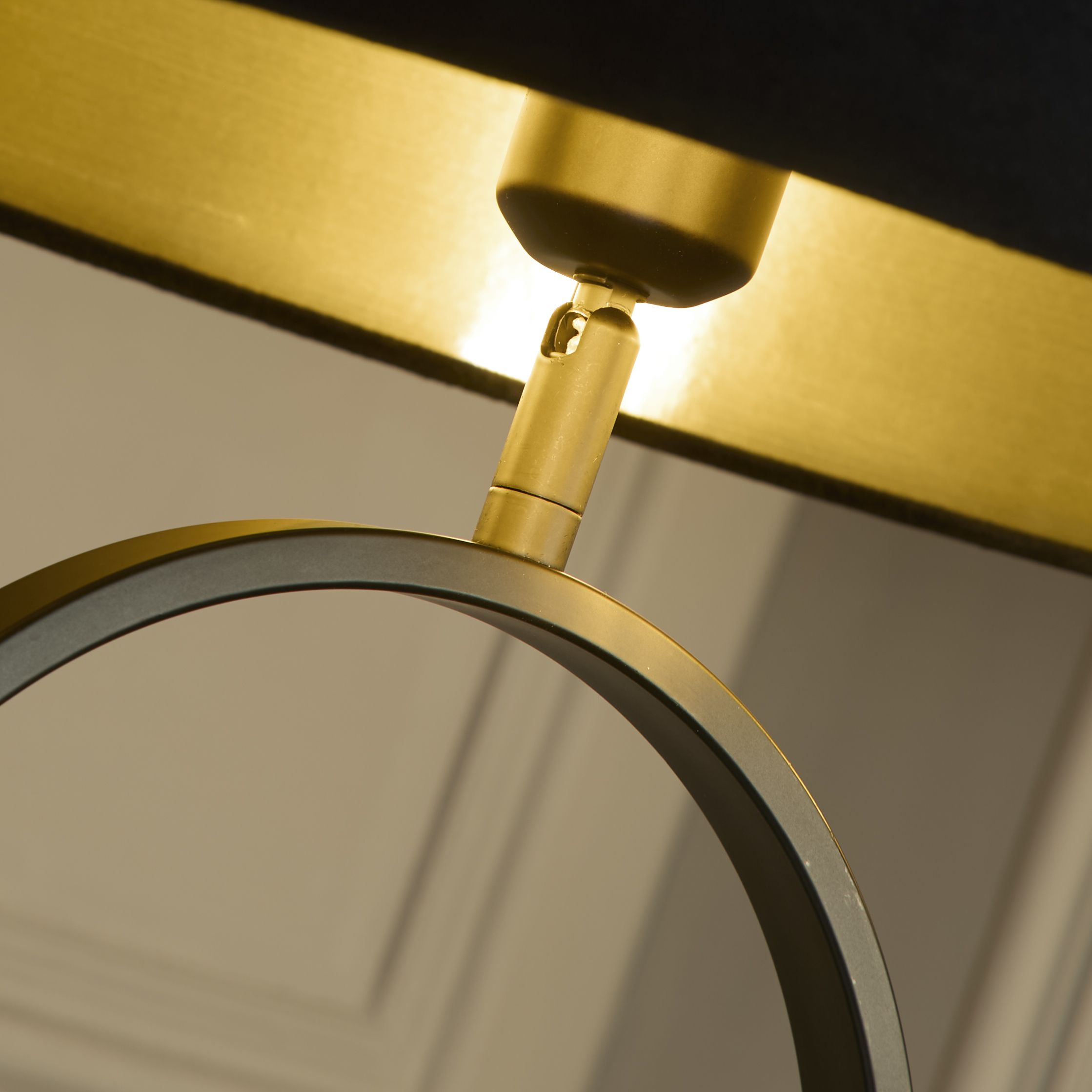 Close up of the brass fitting connecting the black velvet shade to the black oval frame of the Modish floor lamp