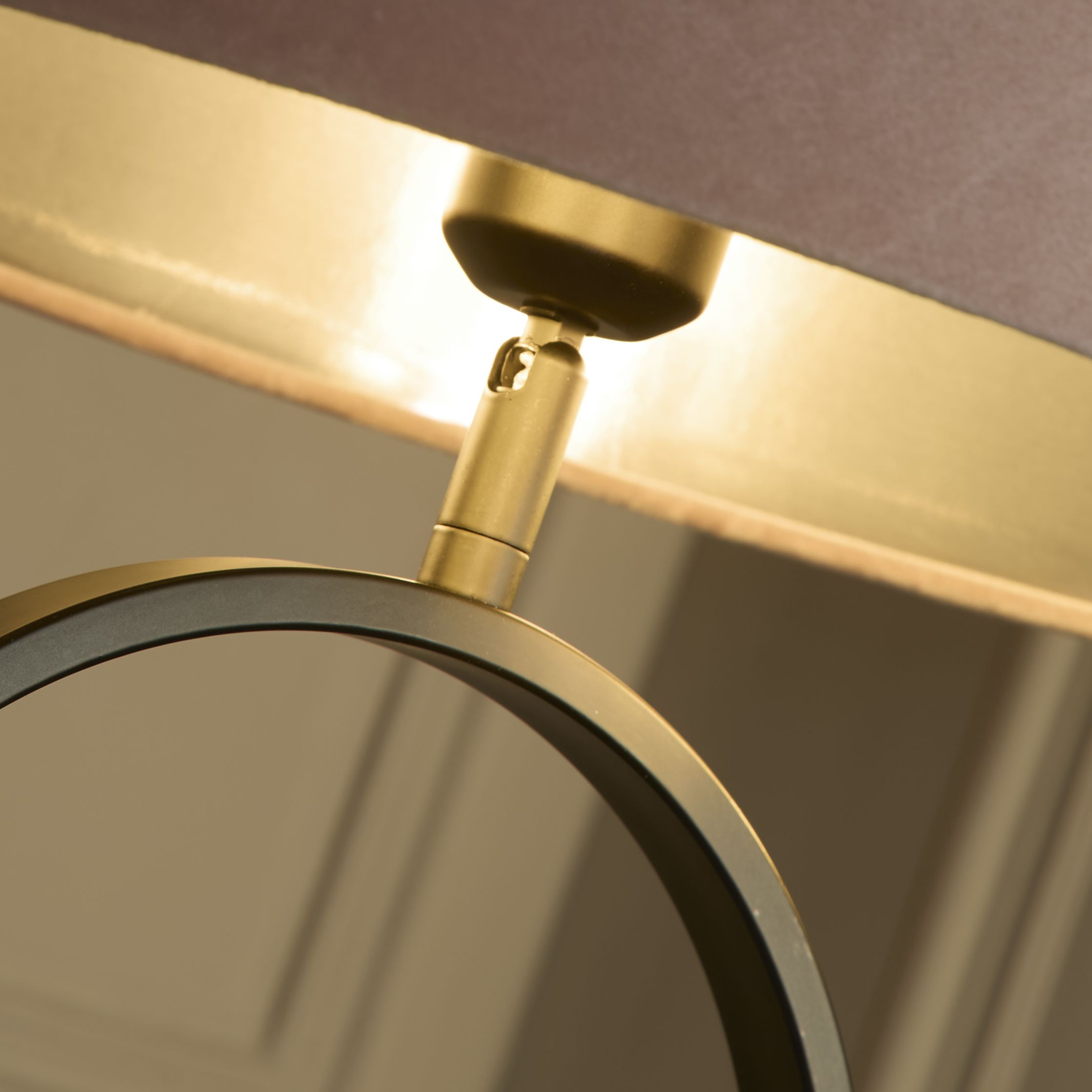 Close up of the brass adjustable joint connecting the pink velvet shade to the black oval ring base