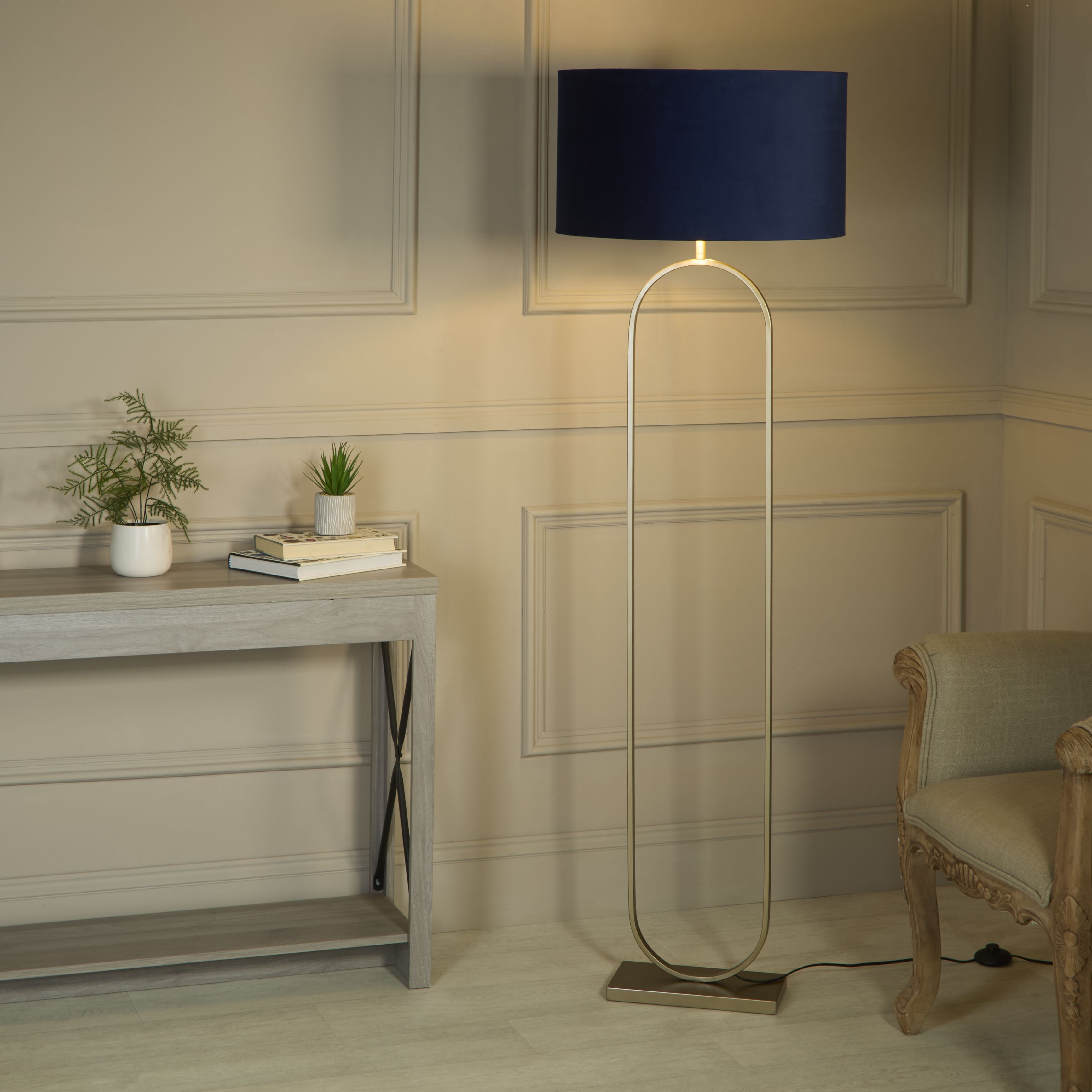 Searchlight Modish floor lamp with navy velvet shade switched on beside a console table and armchair in a panelled hallway