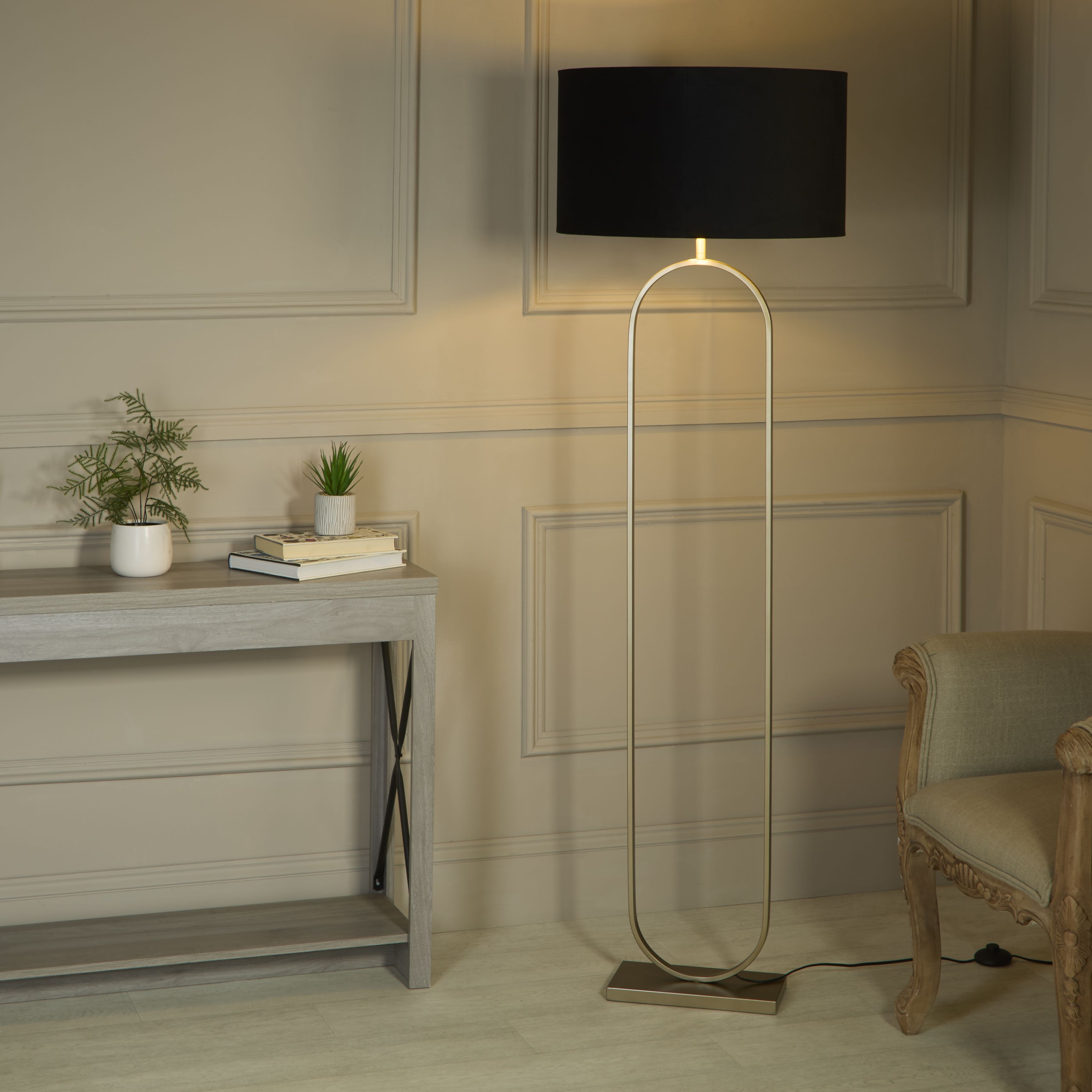 Searchlight Modish floor lamp with black velvet shade switched on beside a console table and armchair in a panelled hallway