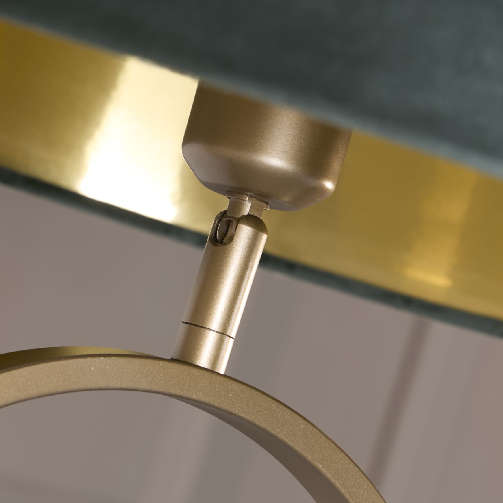 Close up of the bronze oval frame and adjustable fitting where the green velvet shade attaches, showing the gold interior shade lining
