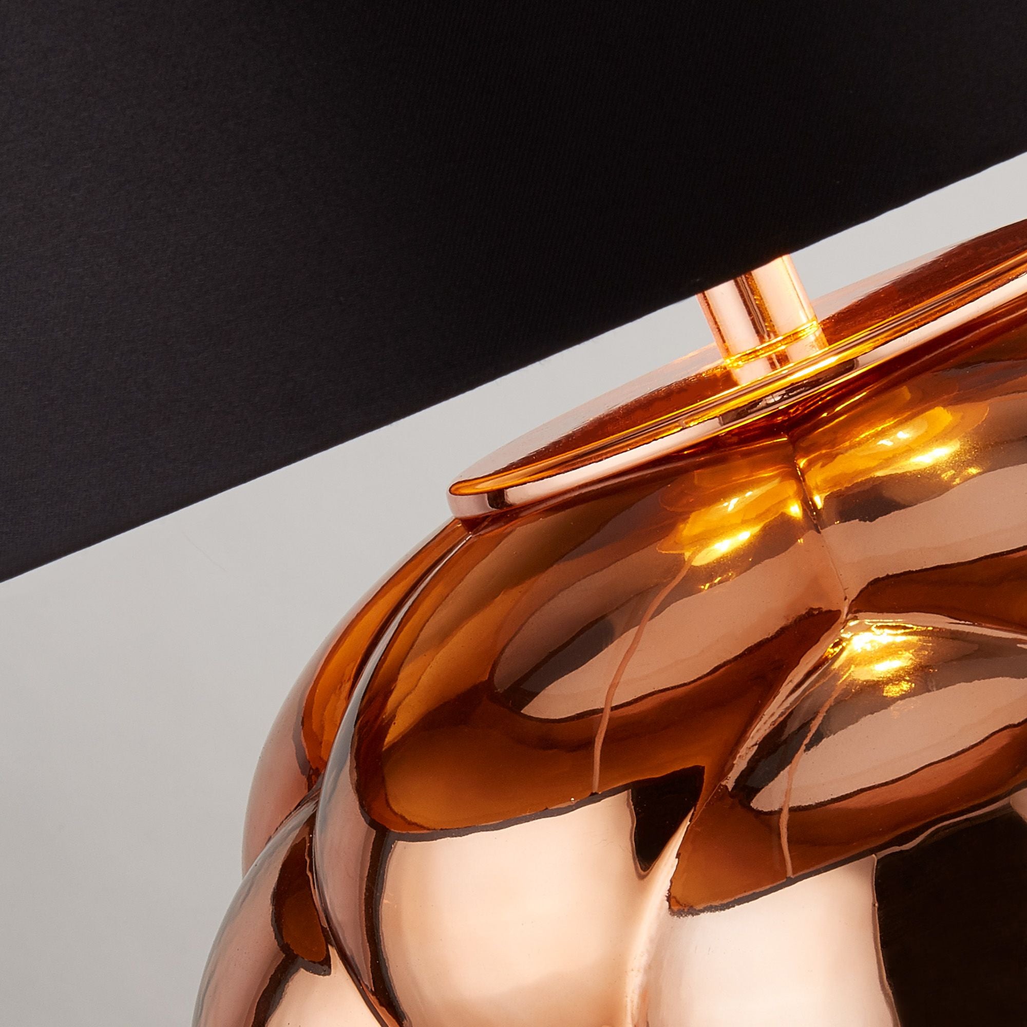 Close up of the Fizz table lamp base, showing the bubbled copper glass texture and the copper coloured inner lining of the shade, lit