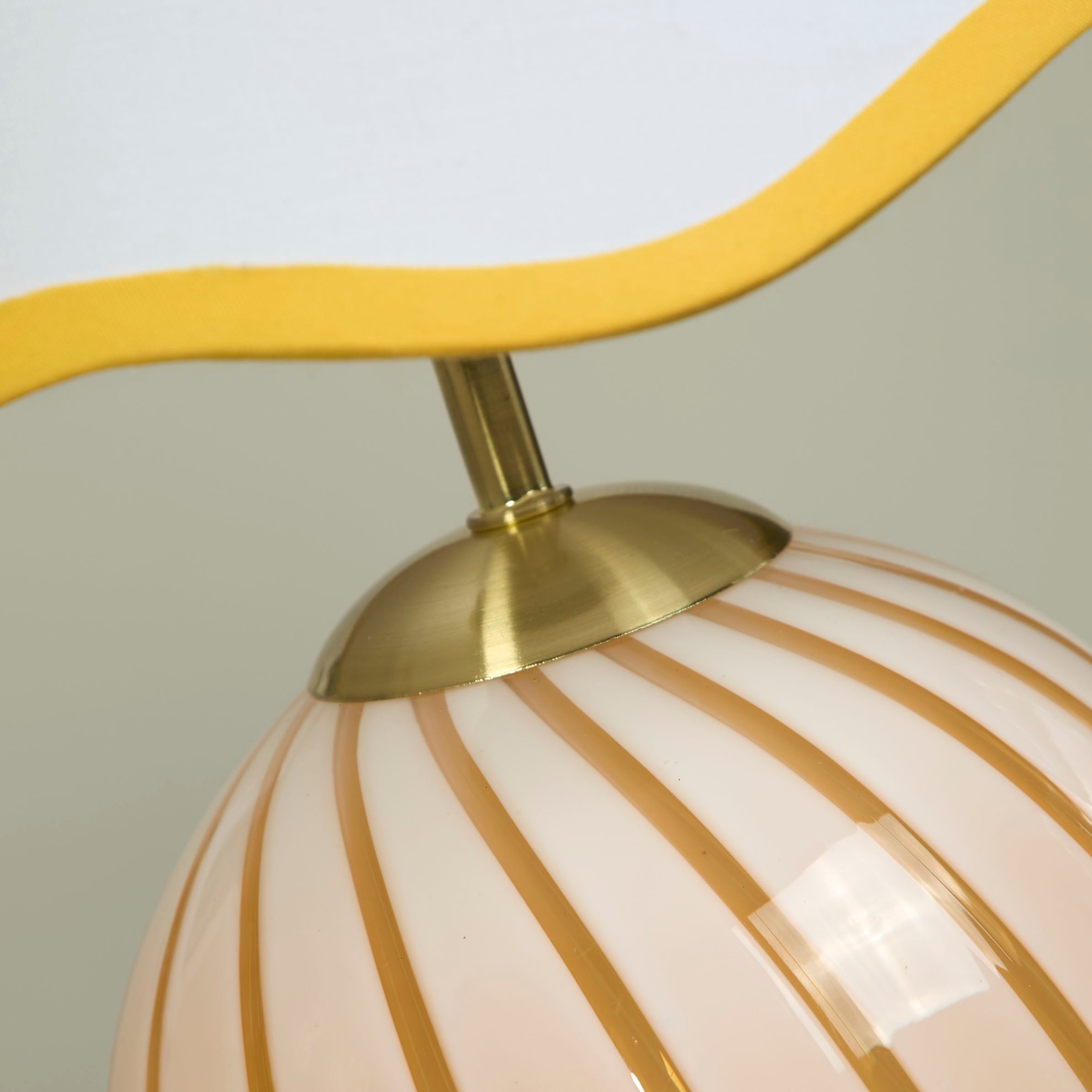 Close up of the Celine lamp's brass gallery fitting and the top of the yellow striped glass globe