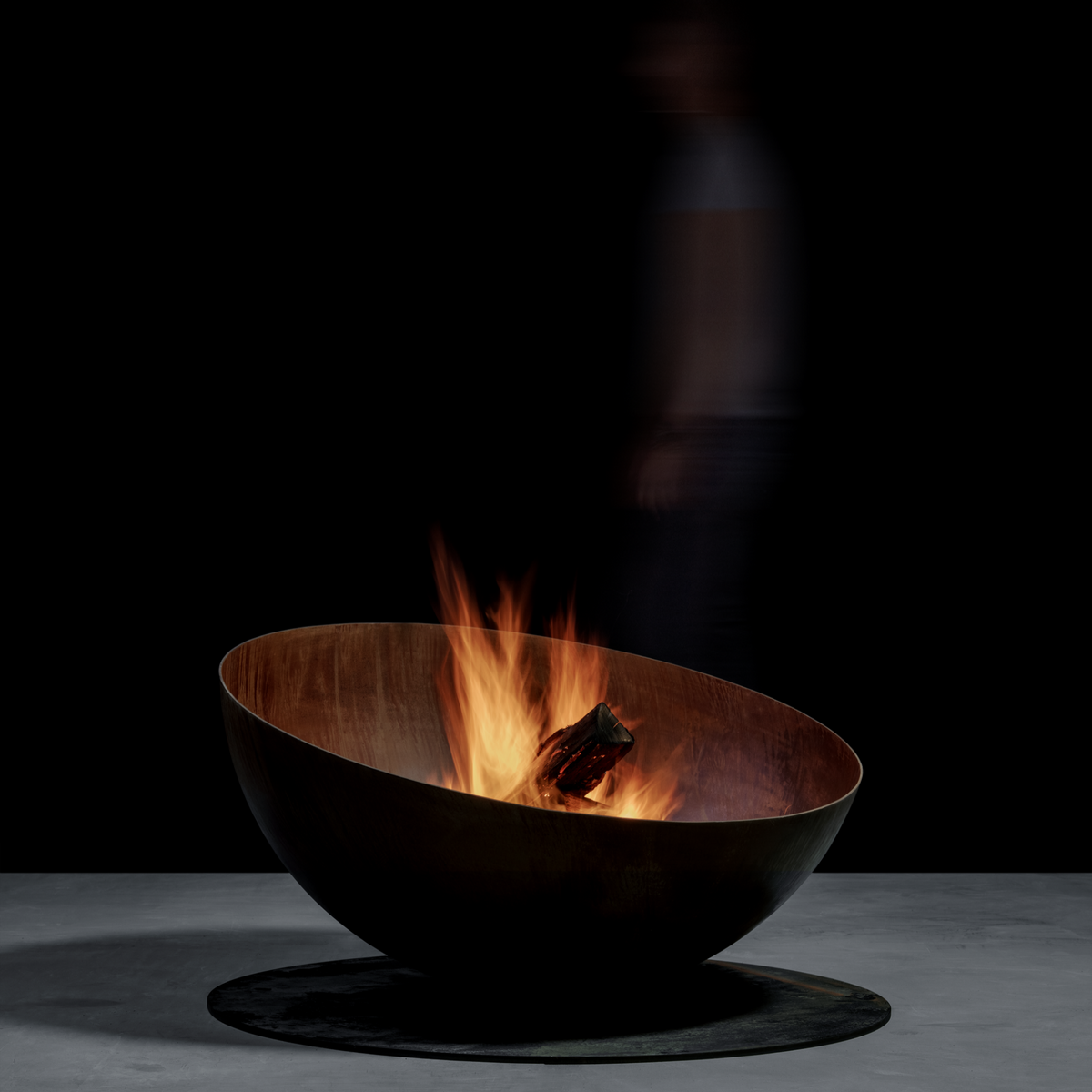 GlammFire Solace round wood burning fire pit showing its sculptural rusted steel bowl and natural flames