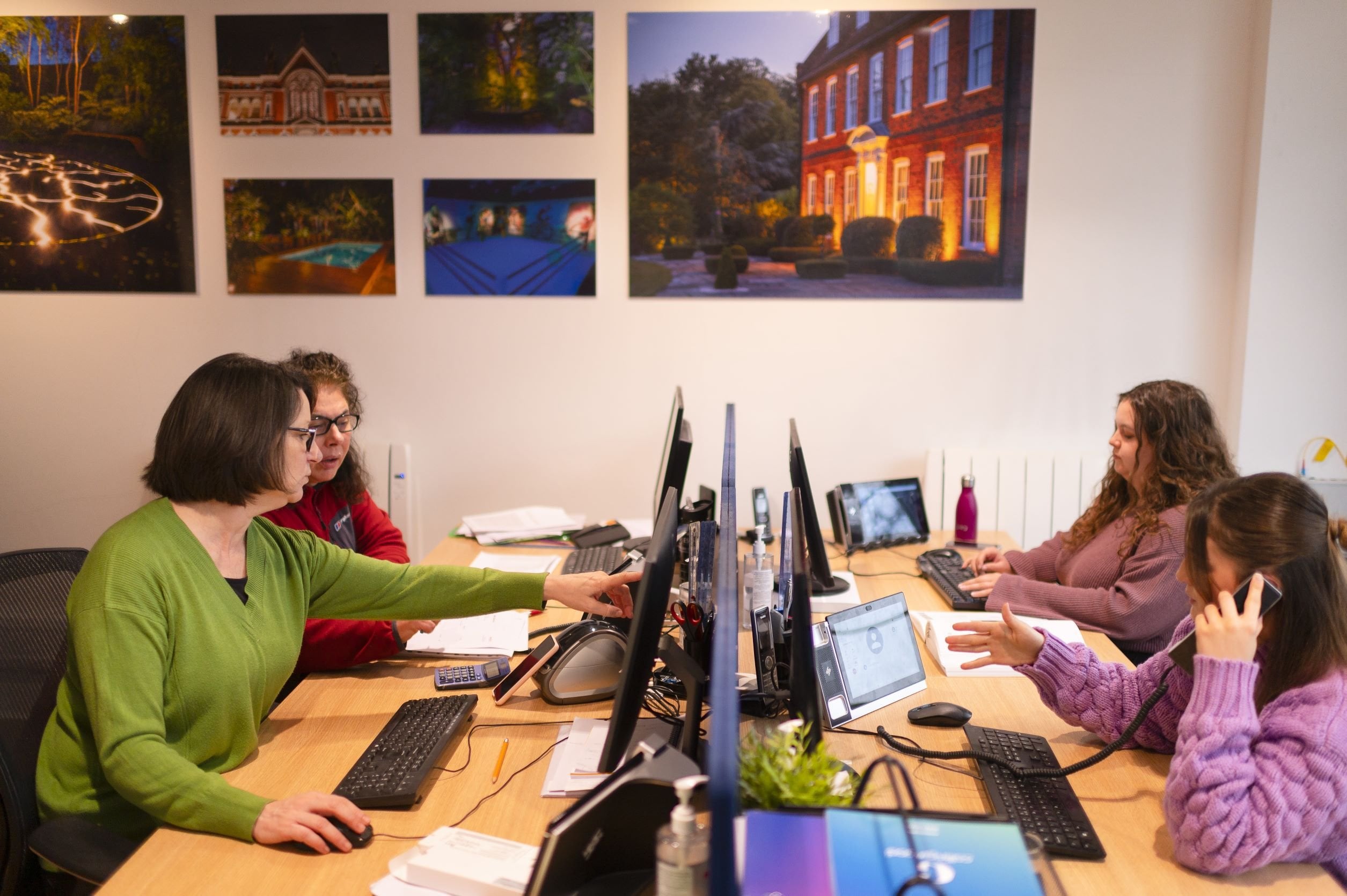 People working at a desk with computers in an office setting.