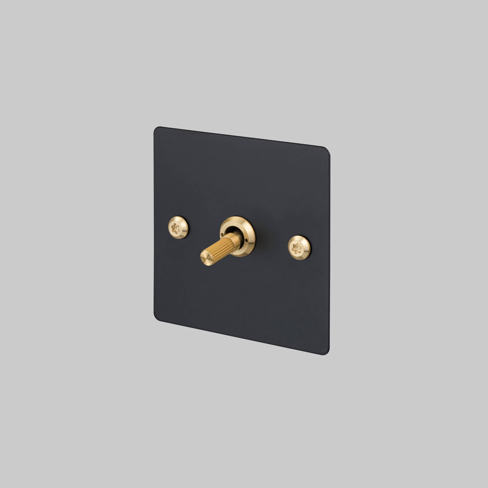 Buster + Punch 1G 2 way toggle switch, Black plate with Brass linear knurl toggle arm, front view
