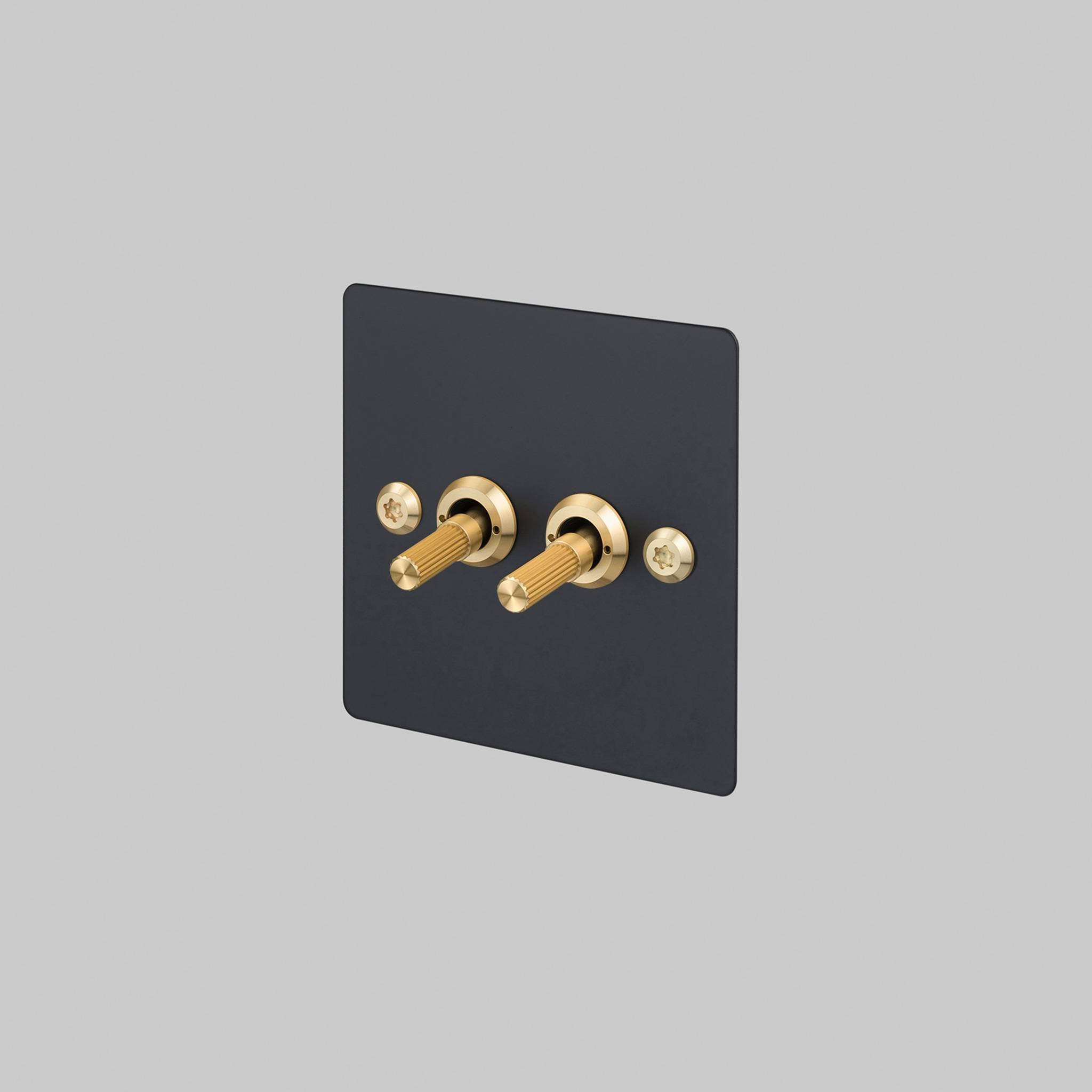 Buster + Punch 2G 2-way toggle switch, black plate with brass linear knurl toggle arm, front view