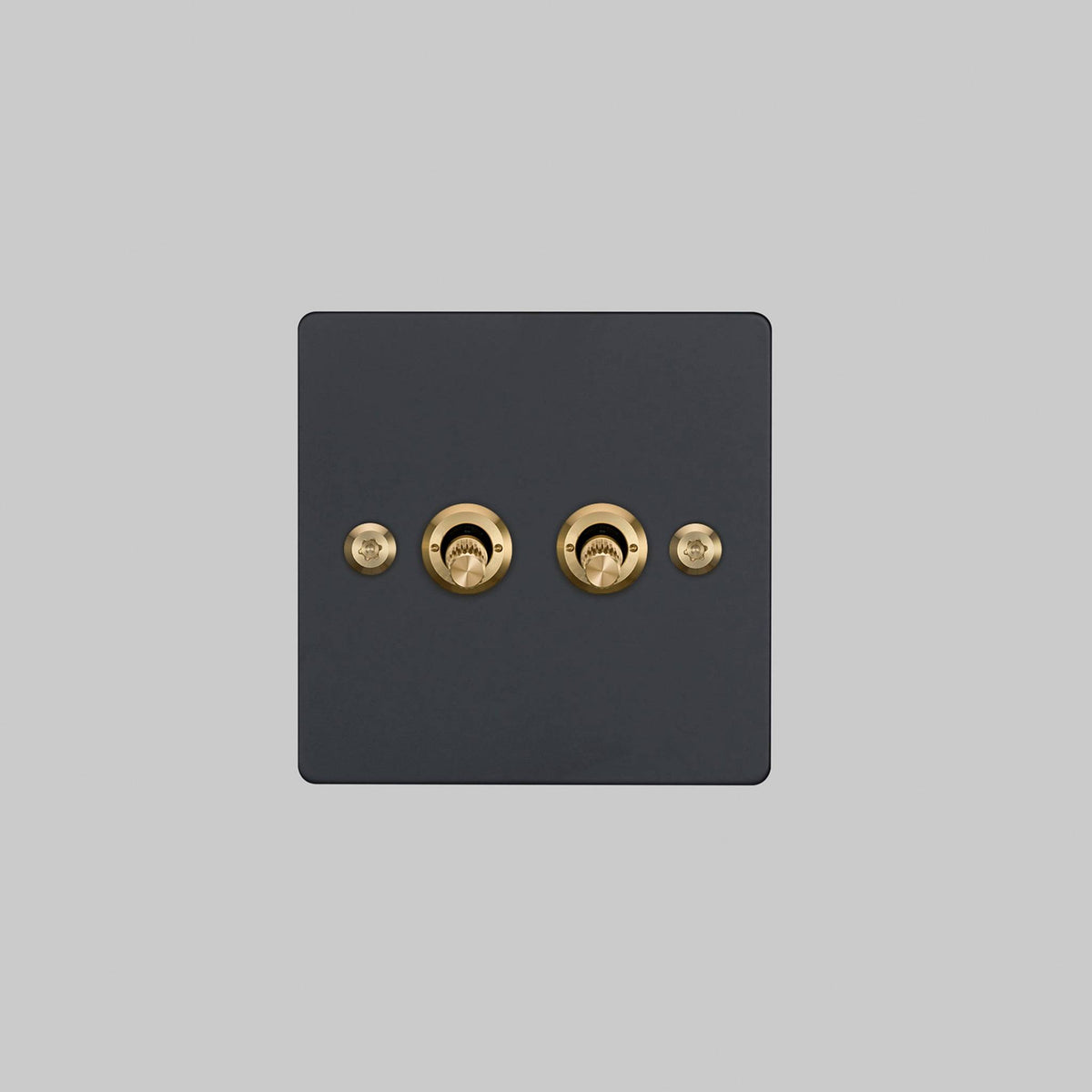 Buster + Punch 2G 2-way toggle switch, black plate with brass linear knurl toggle arm, elevated angle view