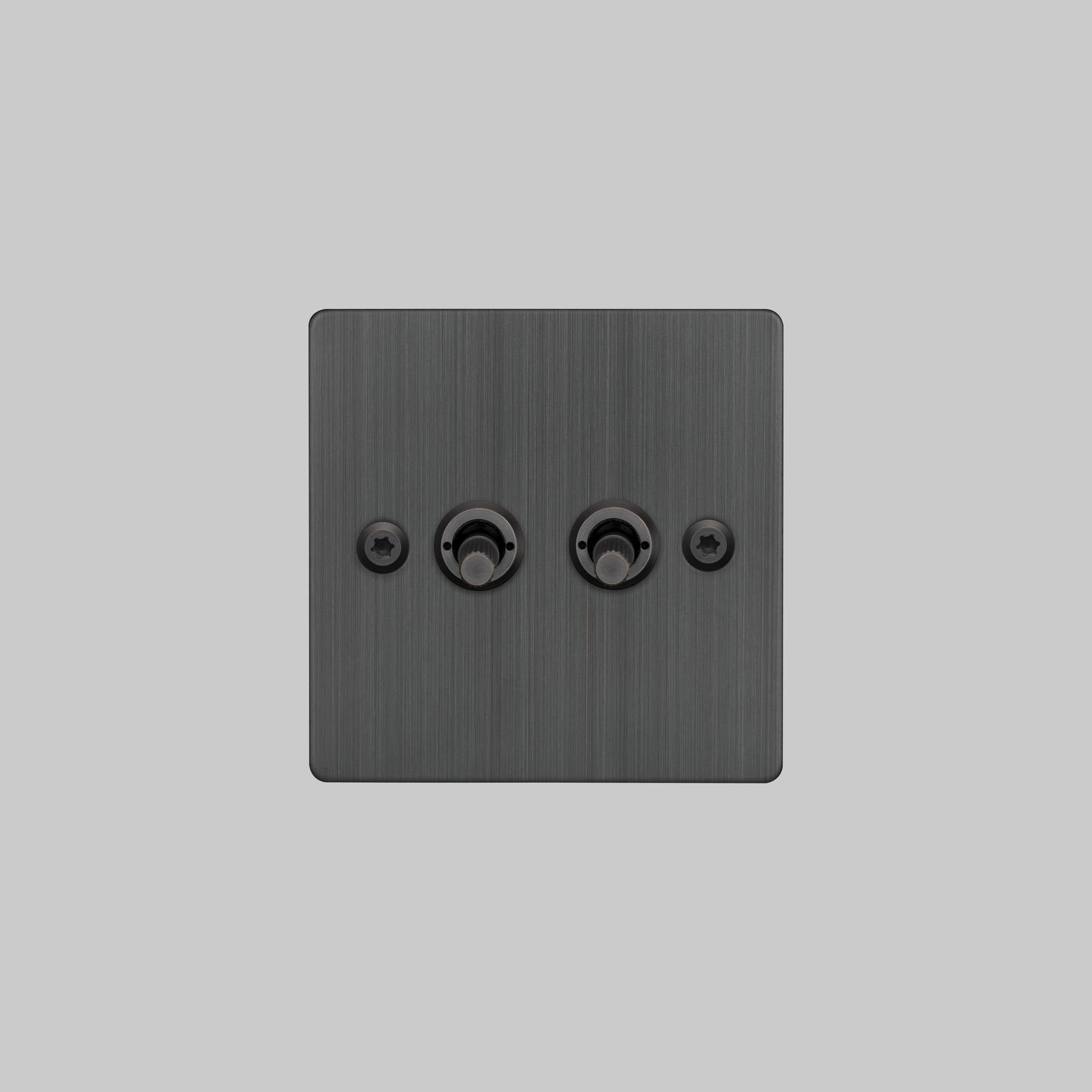 Buster + Punch 2G 2-way toggle switch, smoked bronze plate with smoked bronze linear knurl toggle arm, elevated angle view