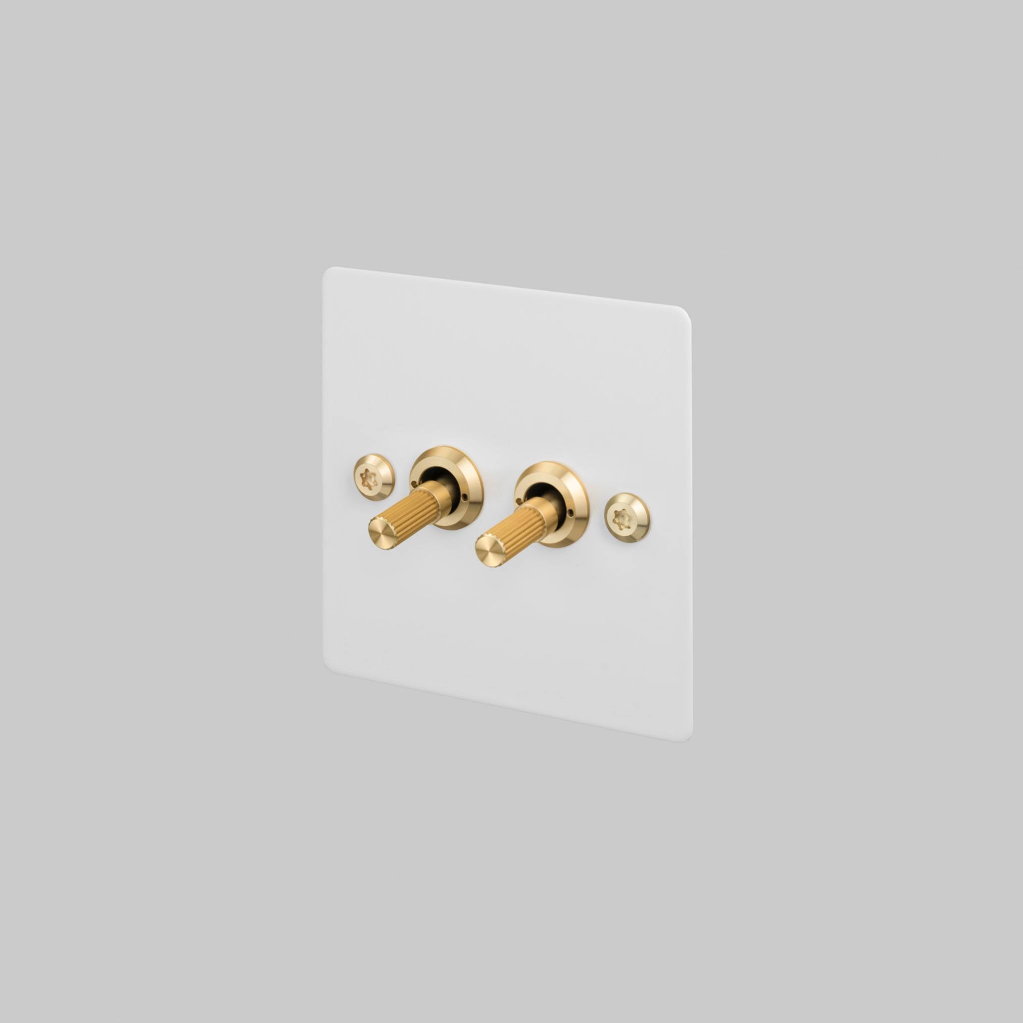 Buster + Punch 2G toggle switch, white plate with brass linear knurl toggle arms, front view