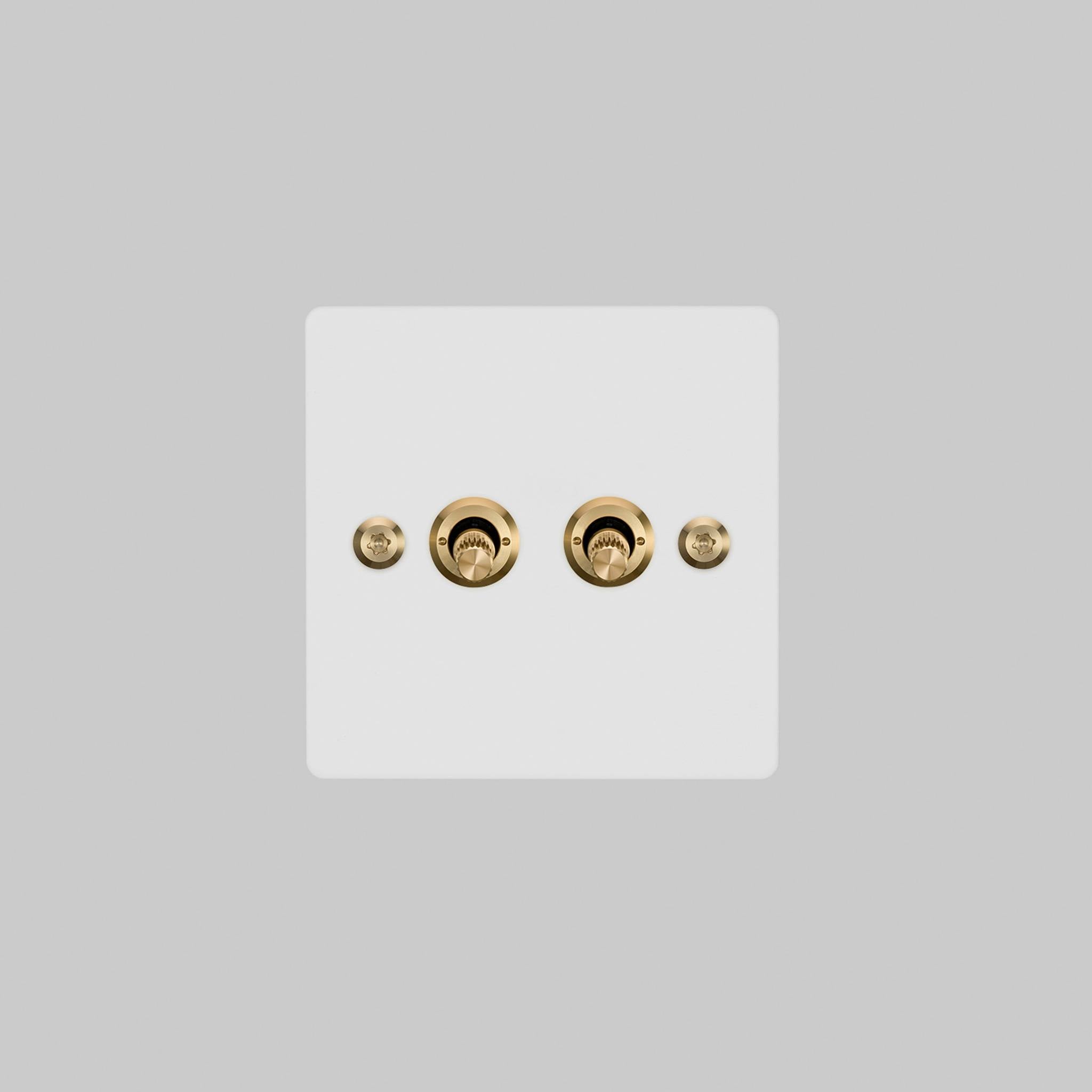 Buster + Punch 2G toggle switch, white plate with brass linear knurl toggle arms, elevated angle