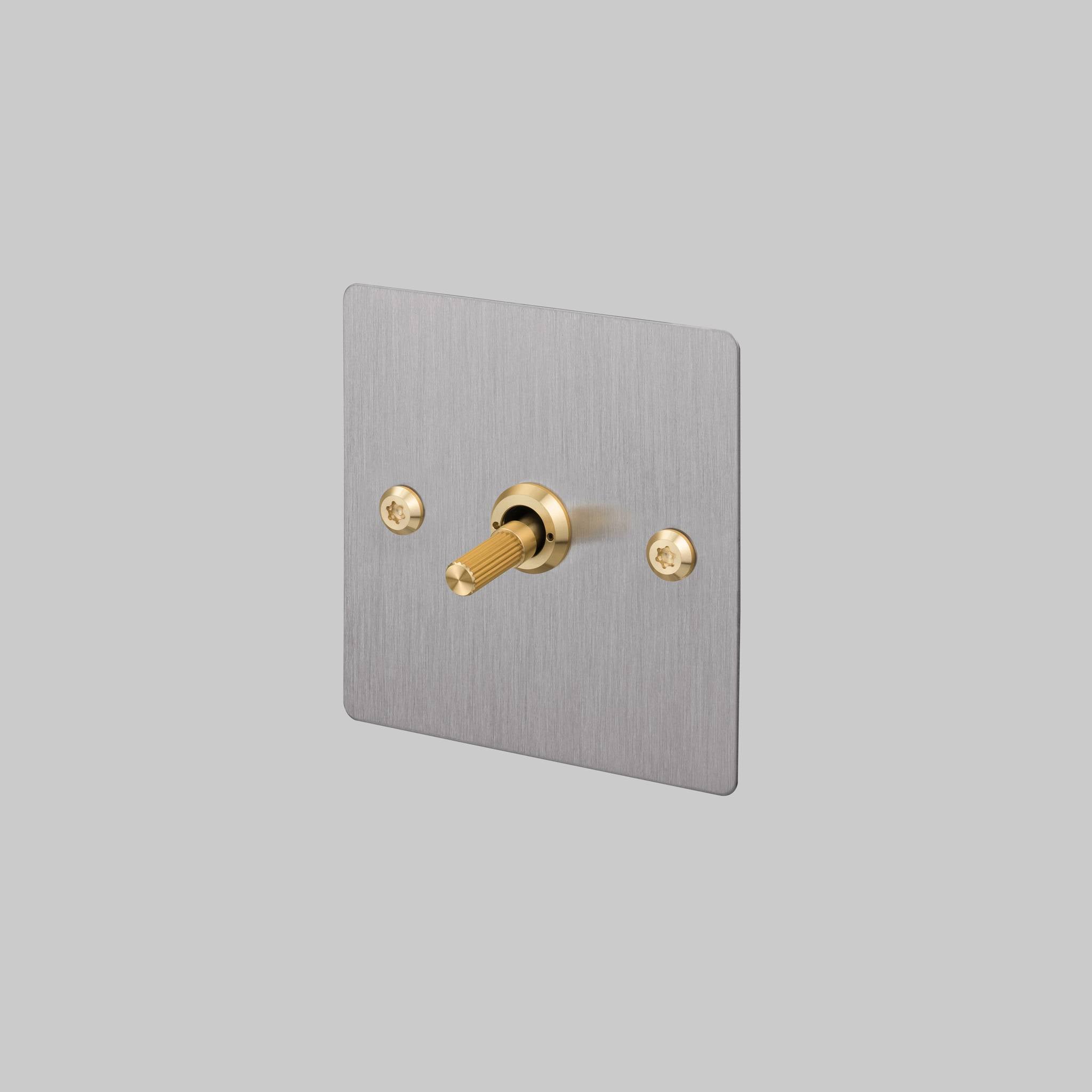 Buster + Punch 1G 2 way toggle switch, Steel plate with Brass linear knurl toggle arm, elevated angle view