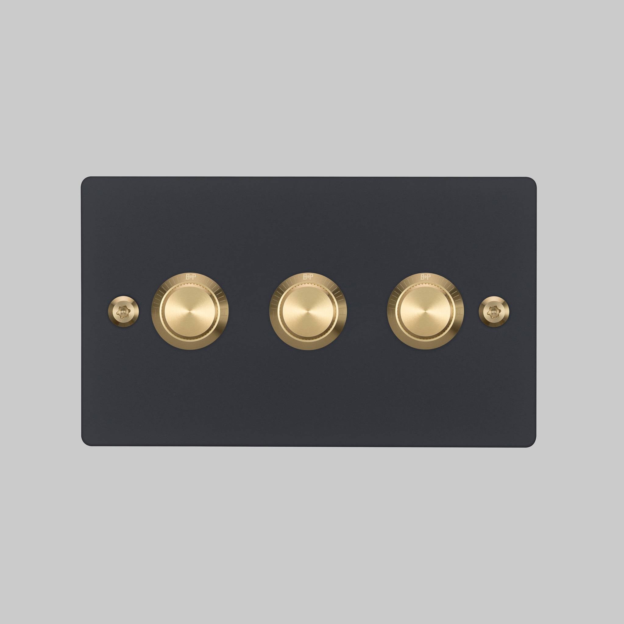 Buster + Punch 3G dimmer switch, black plate with brass linear knurl knobs, elevated angle view