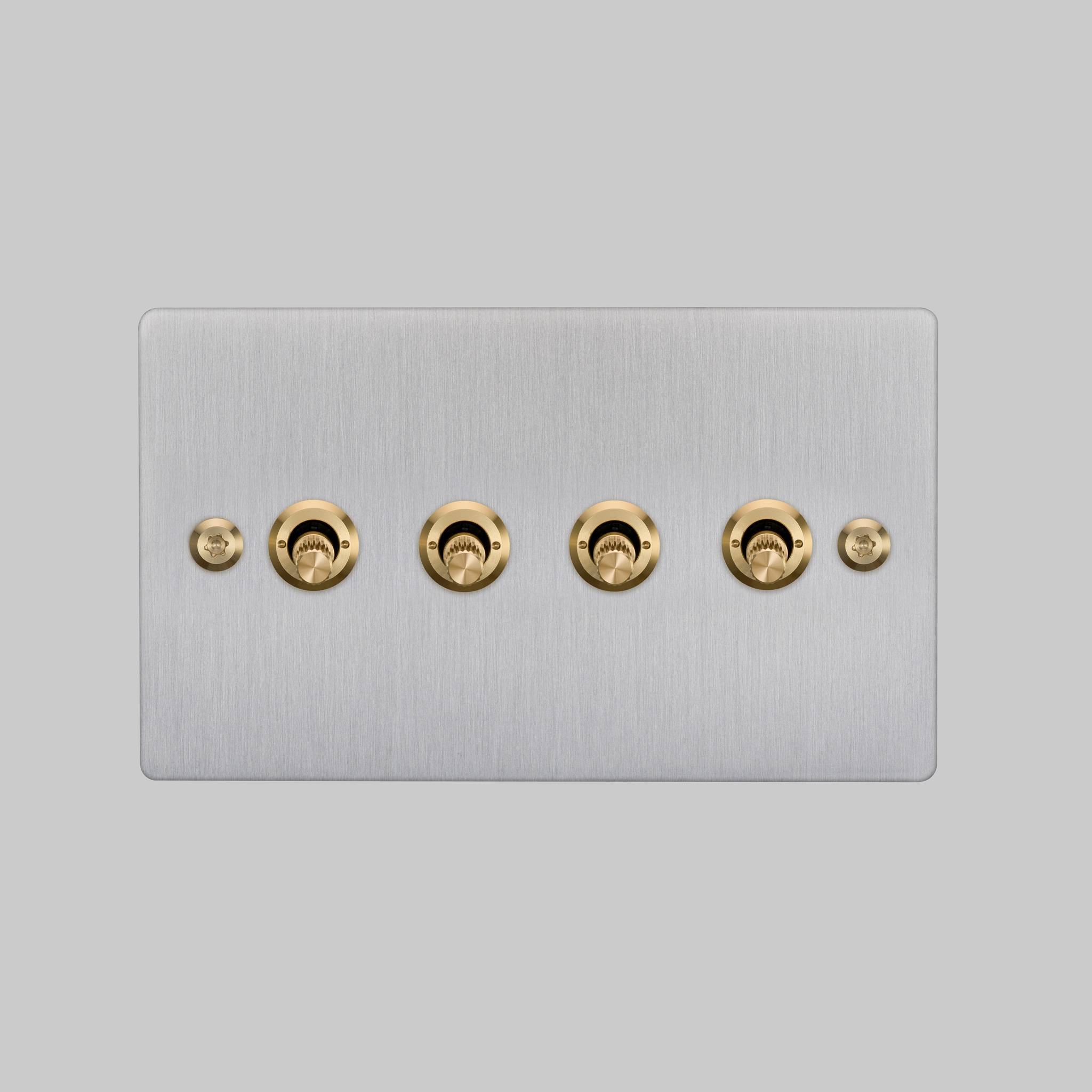 Buster + Punch 4G toggle switch, steel plate with brass linear knurl toggle arms, elevated angle view