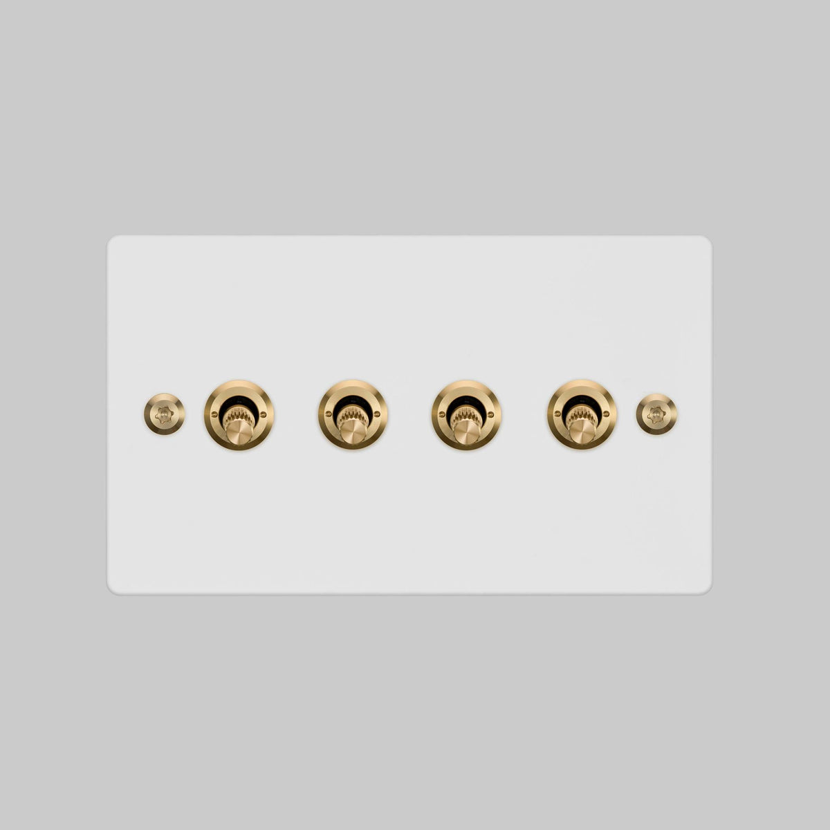 Buster + Punch 4G toggle switch, white plate with brass linear knurl toggle arms, elevated angle view