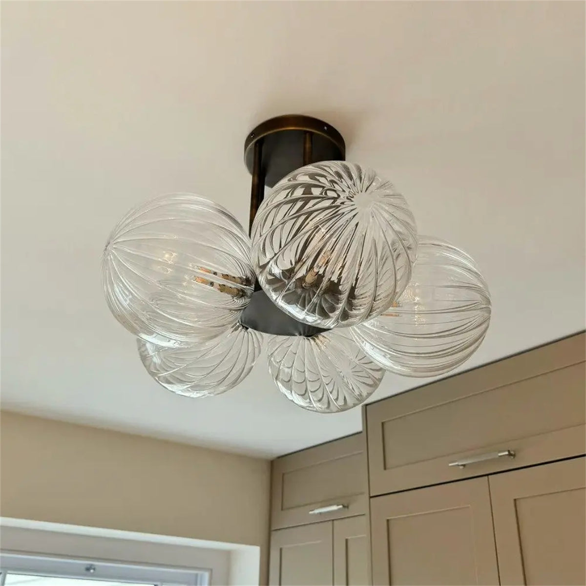 Leverint Pimlico Chandelier 5 Way, five clear ribbed glass globes on a dark ceiling plate, fitted close to the ceiling of a kitchen with taupe cabinets