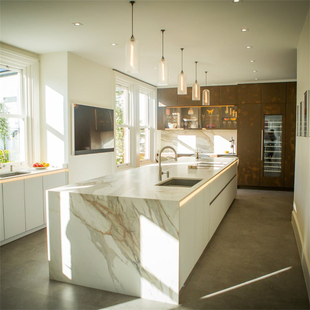Five lit Leverint Richmond pendants in textured glass hung at different heights above a kitchen island with a marble worktop