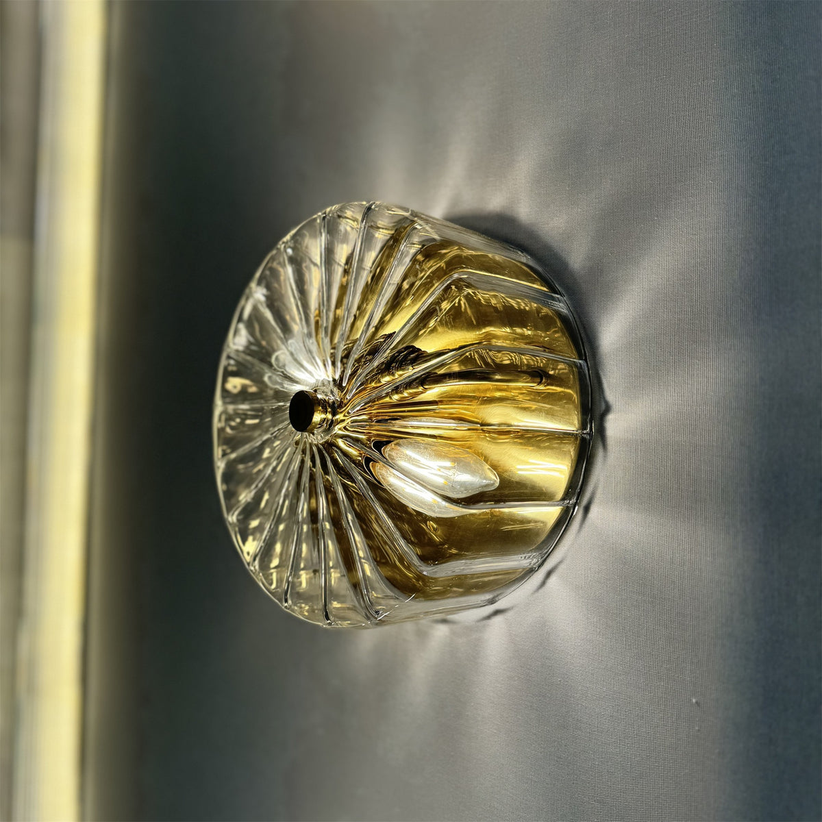 Leverint Temple Flush Mount in ribbed clear glass with a brass finish inside, lit against a grey backdrop with candle bulbs visible