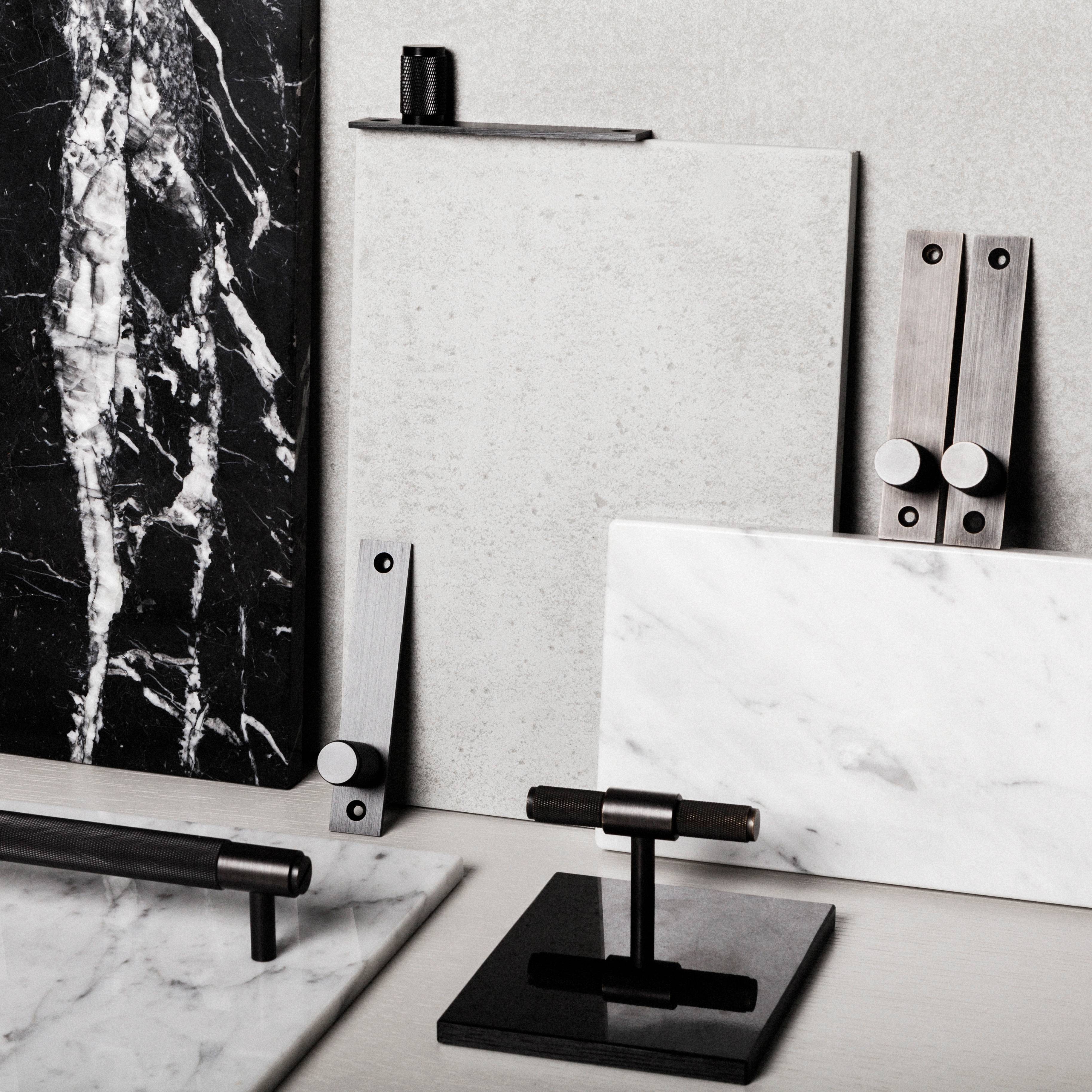 Flat lay of Buster + Punch bar and knob finishes on marble and concrete swatches